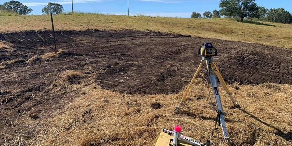 Surveying equipment set up in a rural field under clear blue skies.
