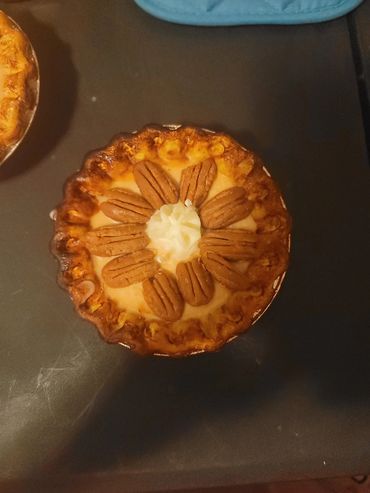 Pecan pie with whipped cream center on a dark surface.