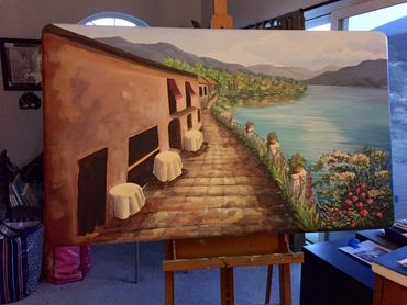 mural painted on large wood table of restaurant tables next to lake