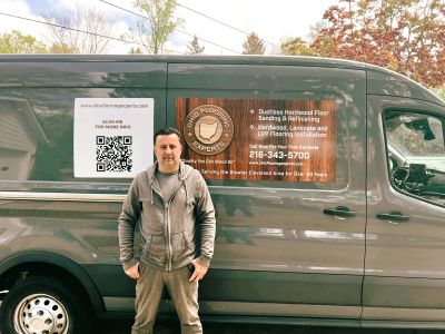The owner and founder of Ohio Flooring Experts, standing in front of the company van, ready for a fr