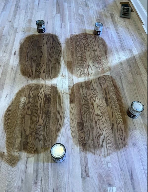 Close-up photograph of several stain colors tested on a sanded hardwood floor in Beachwood, OH