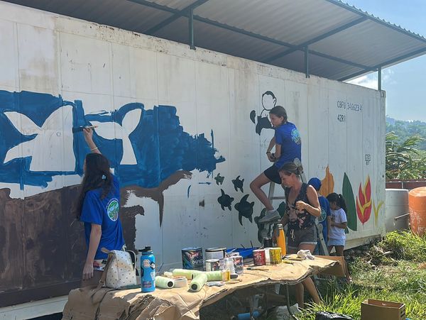 Volunteers painting a sea turtle and ocean-themed mural during a service project in Costa Rica.