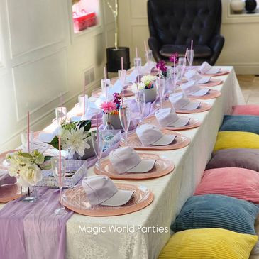 Elegant party table setup with pastel cushions and floral centerpieces.