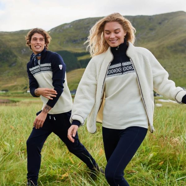 A man and woman smiling while hiking outdoors wearing a Norwegian sweater from Dale of Norway