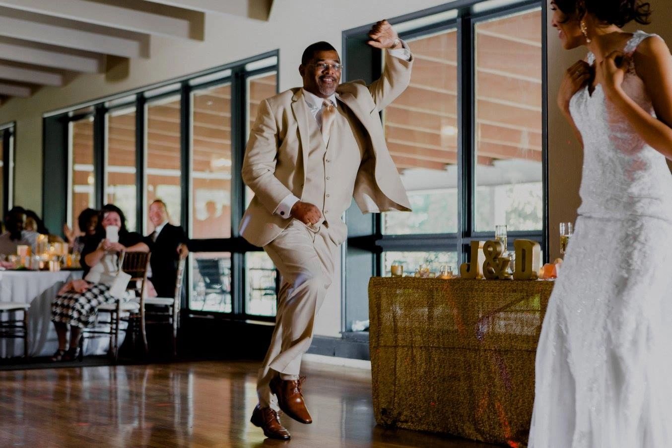 Man in suit joyfully dancing at wedding reception near bride.