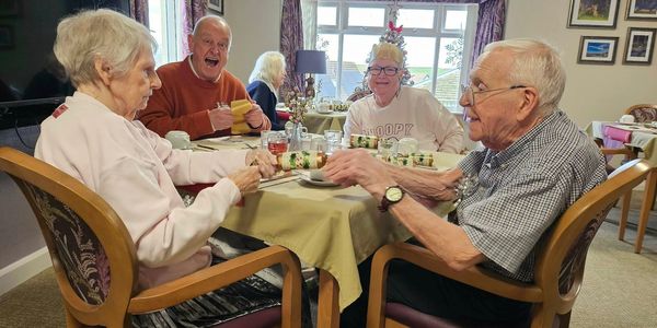 A family enjoying a meal at a dining table. Everyone looks happy and content