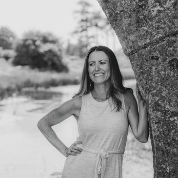 Business owner Sarah standing by a river leaning against a wall