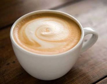 A creamy latte with a swirl of frothy milk in a white ceramic cup.