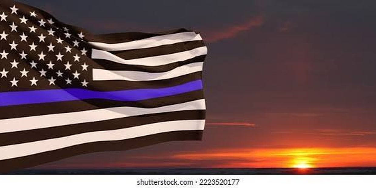 Black-and-white American flag with a blue stripe at sunset.
