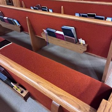 Church pews with hymnals and Bibles neatly arranged in holders.