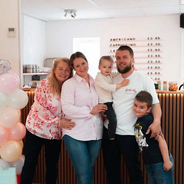 A smiling family of five posing together in a cozy café setting.