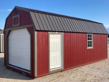 Red barn-style shed with white door and garage-style roll-up door.