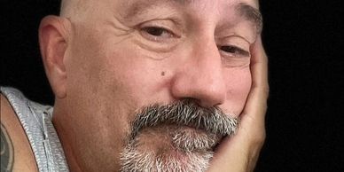 Close-up of a contemplative man resting his face on his hand.