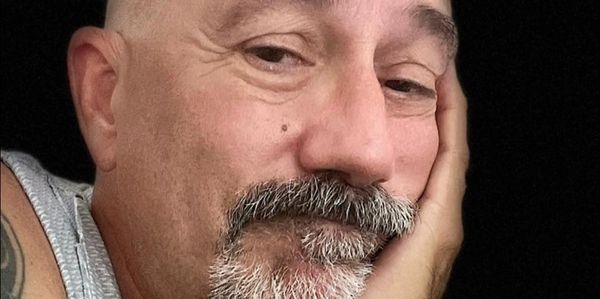 Close-up of a contemplative man resting his face on his hand.