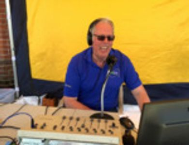 Man in blue shirt hosting a radio show with headphones and microphone.