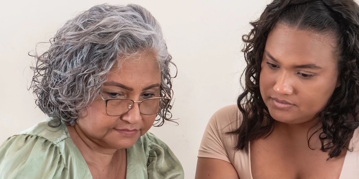 Two women with curly hair focus on something in front of them.