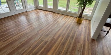 Room with wooden laminate flooring and large glass doors.