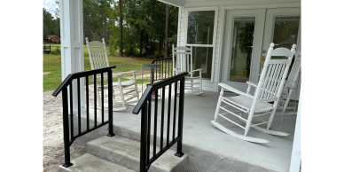 White rocking chairs on a porch with black railings.