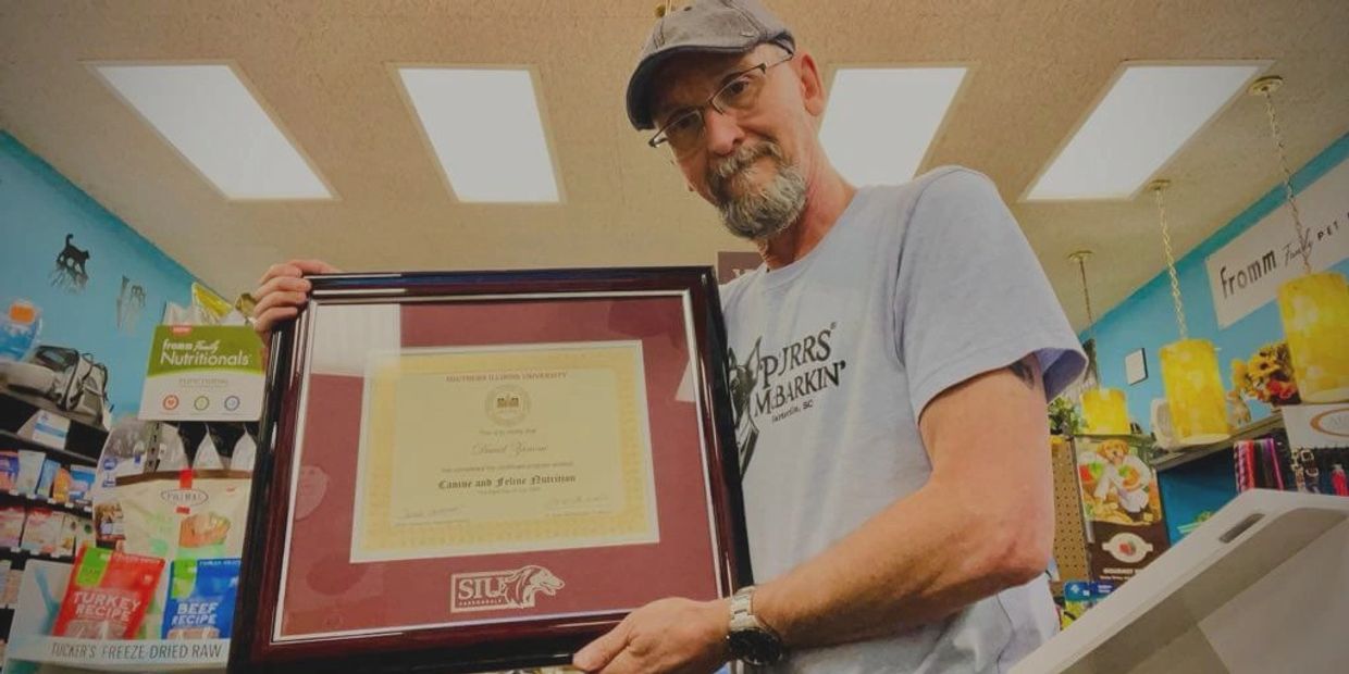 Dave, certified canine and feline nutritionist  proudly holds his framed certification from SIU.