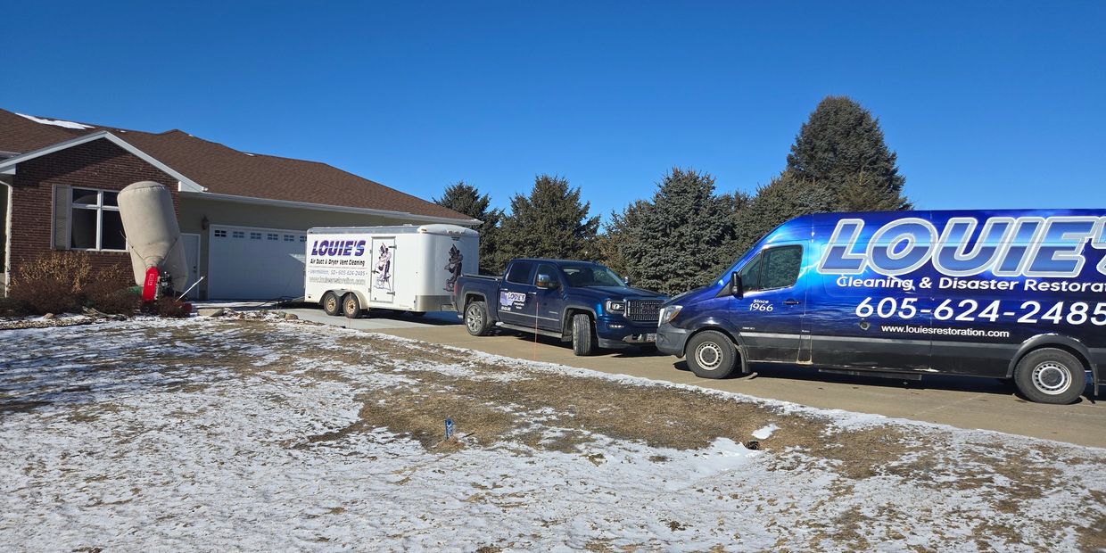 Louie's Cleaning and Disaster Restoration trucks and trailer at a water damage job