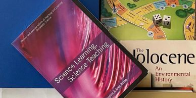 Two books and a board game with dice on a table.