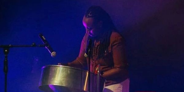 Musician playing steelpan with microphone on stage.