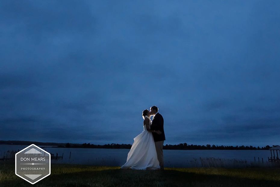 A couple sharing a romantic moment under a dusky sky by the water.