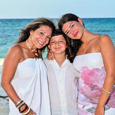 Three people smiling at the beach.
