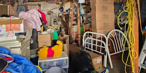 Cluttered storage room filled with boxes, furniture, and miscellaneous items.