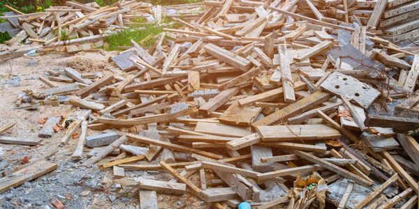 A large pile of scattered wooden planks and debris outdoors.
