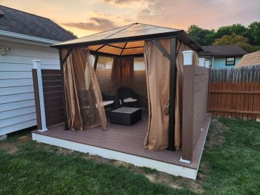 Cozy patio gazebo with curtains at sunset.