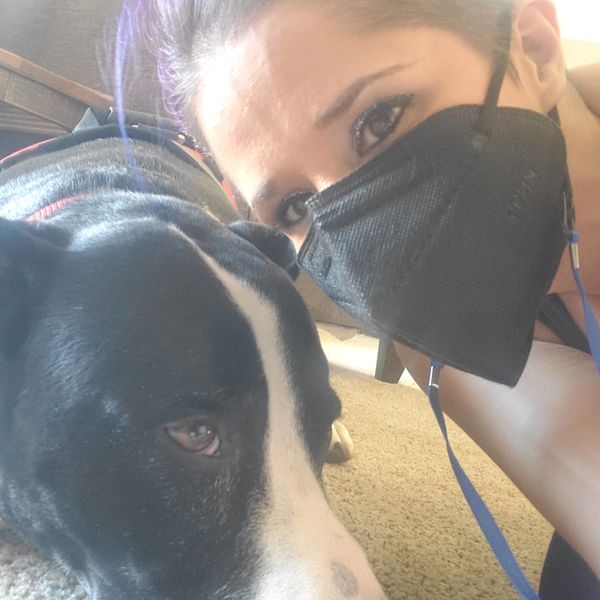 woman wearing black face mask next to black and white dog