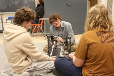 Teens working on a robotics project in a classroom.