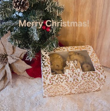 Festive Christmas cookies in a decorative box beside holiday greenery and a bow.