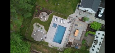 Aerial view of a backyard with a swimming pool, patio, and garden area.