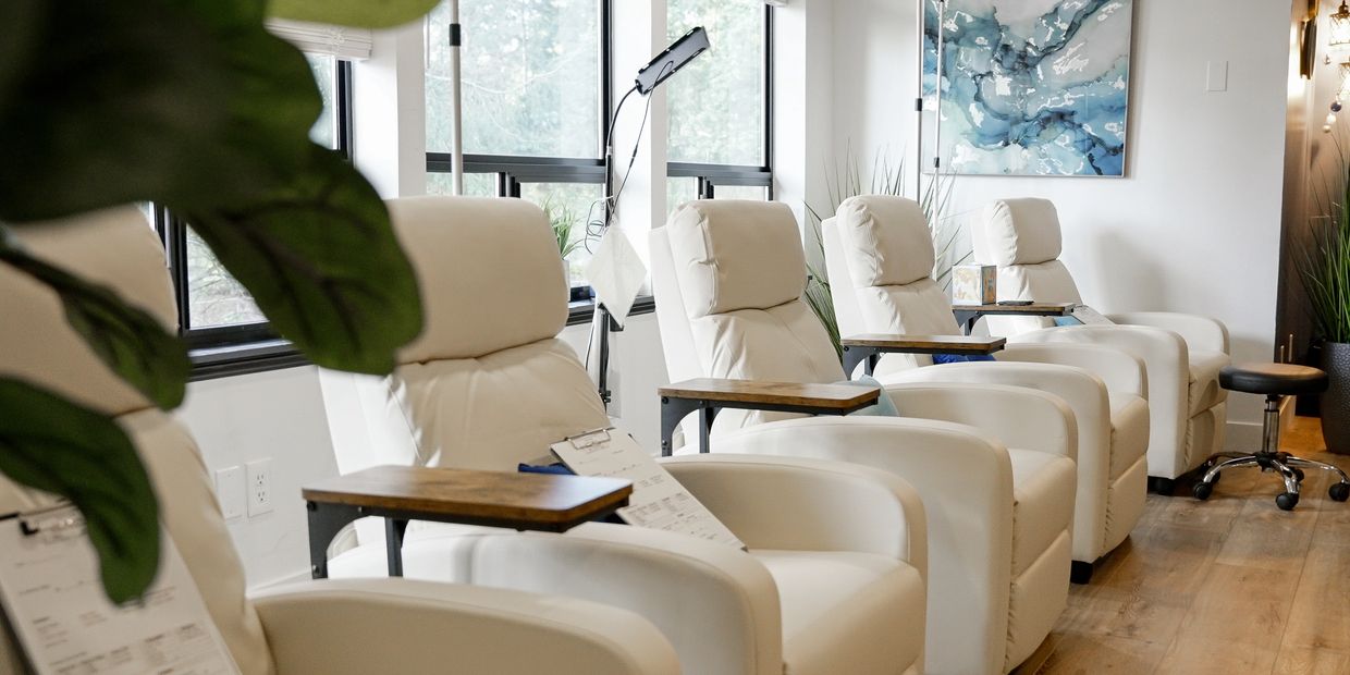 Five white chairs in a row sitting empty at the Revive Drip Gig Harbor Clinic Location.