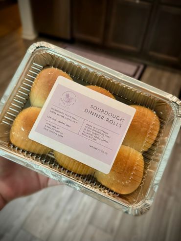 Package of sourdough dinner rolls with a clear lid and label.