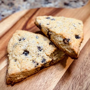 Two chocolate chip scones on a wooden board.