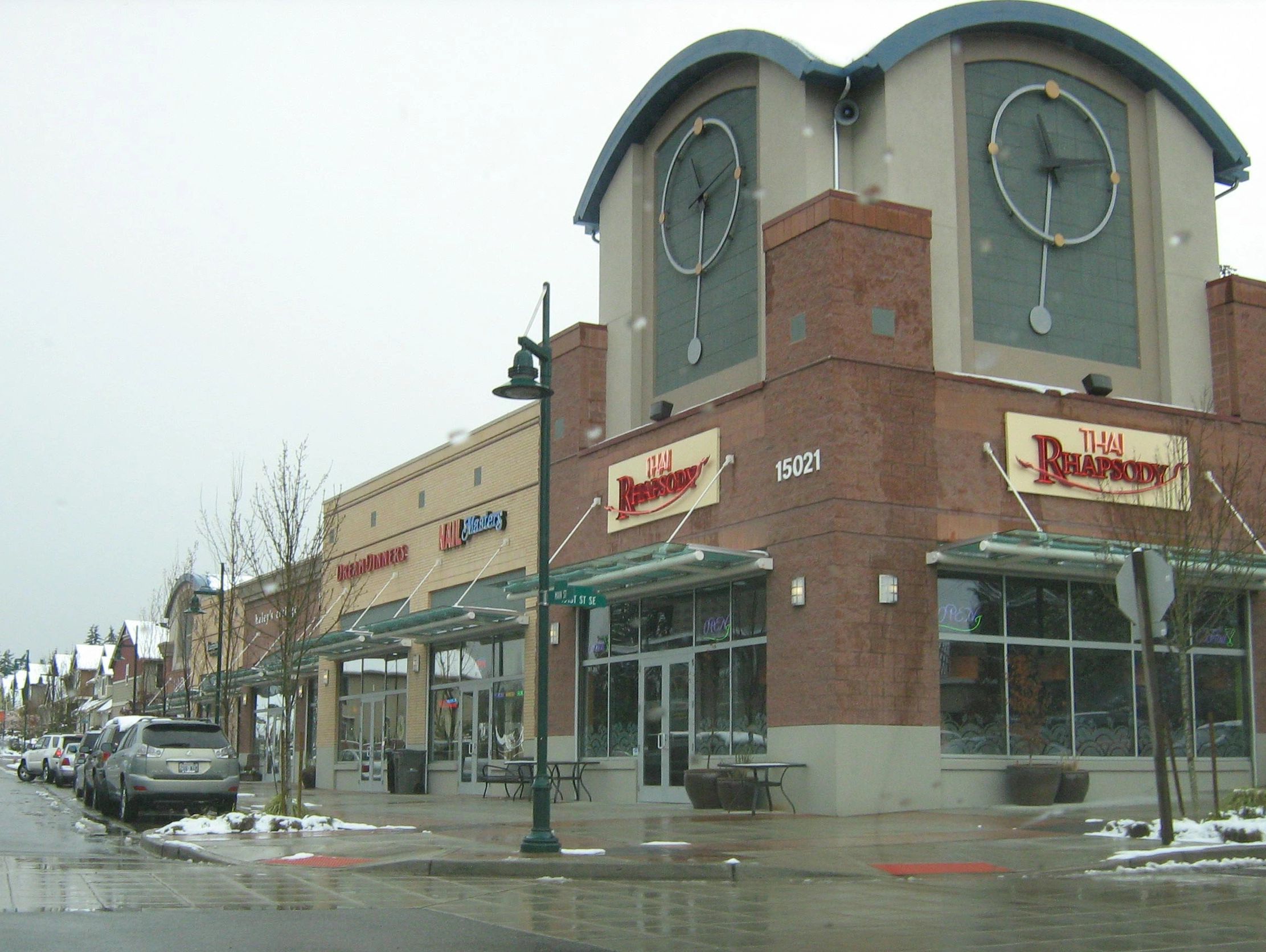 tall building with a clock design on top net to a street with cars