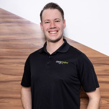 Jeune homme souriant portant un polo noir.