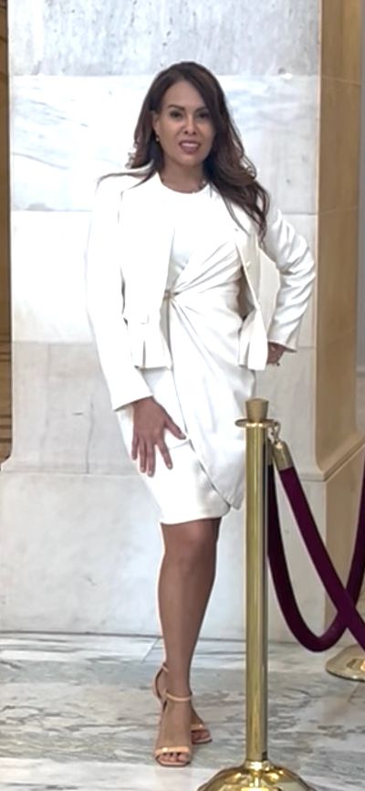 Woman in elegant white dress posing indoors.