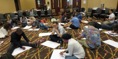 SJTI participants sitting on the floor doing an activity with newsprint paper. 