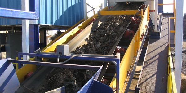 Shredded scrap passing through a Gamma-Tech analyzer on the conveyor