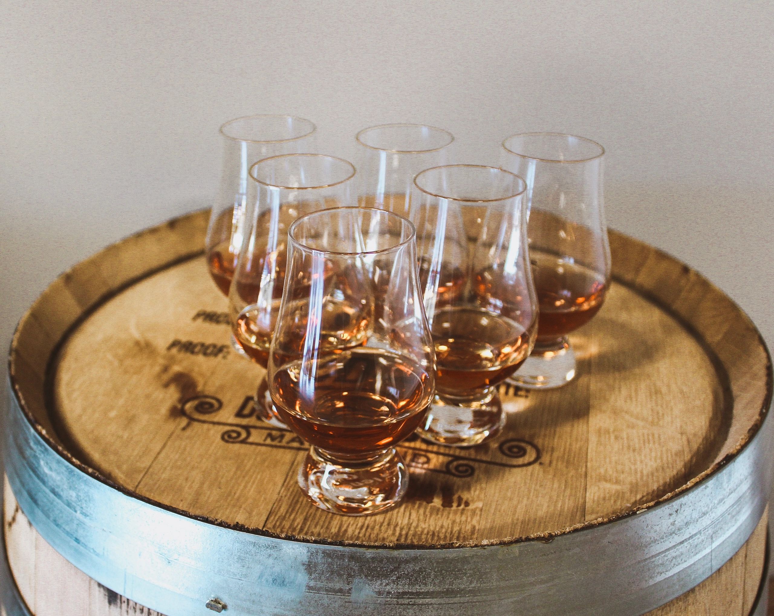 Six glasses of whiskey on a wooden barrel.