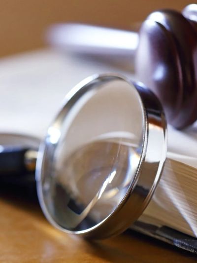 Magnifying glass and gavel on a book.