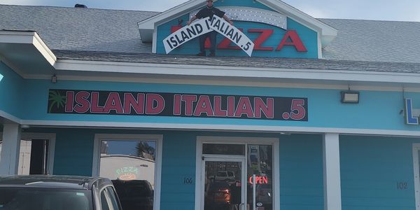 Blue building with a sign reading Island Italian .5 and an open pizza restaurant.