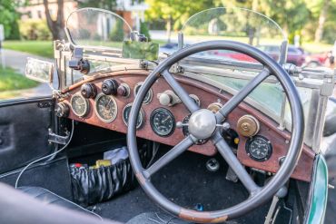 Dashboard of a vintage car with wooden panel and classic gauges.