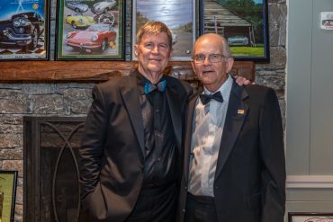 Two men in formal wear posing together indoors.