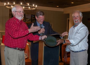 Three men in a celebratory moment during an award presentation.