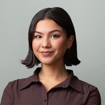 Confident young woman with short dark hair wearing a striped shirt.